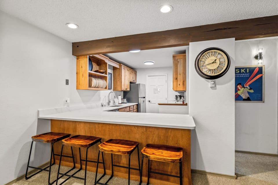 Gather around the breakfast bar for morning coffee or après-ski snacks in your fully-equipped kitchen, complete with warm wood accents, modern appliances, and mountain-inspired decor.