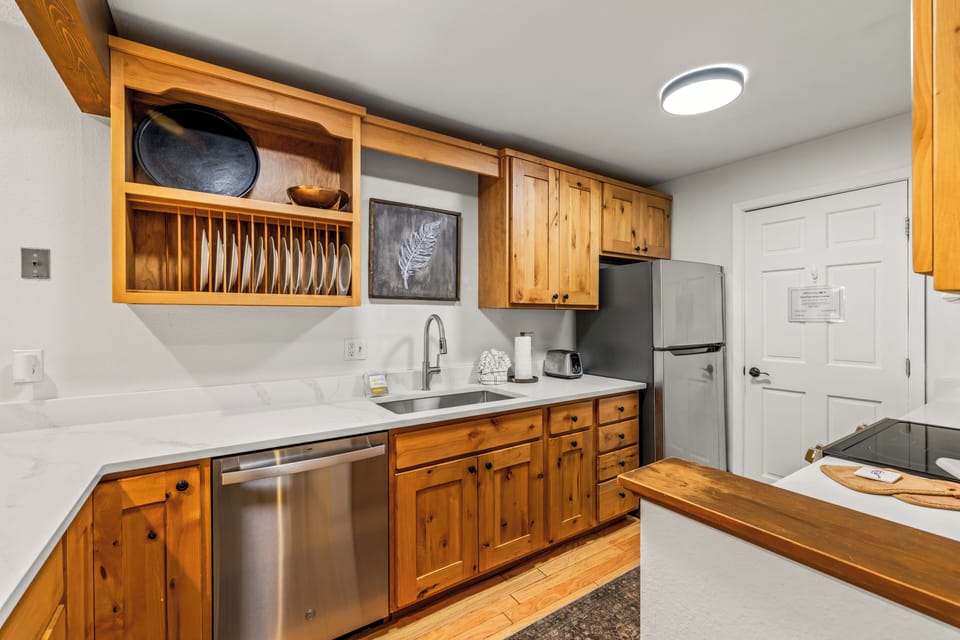 Cook your favorite meals in this fully equipped kitchen with warm pine cabinetry, marble countertops, and stainless appliances. Everything you need is here, from the built-in plate rack to dishwasher and full-size fridge.
