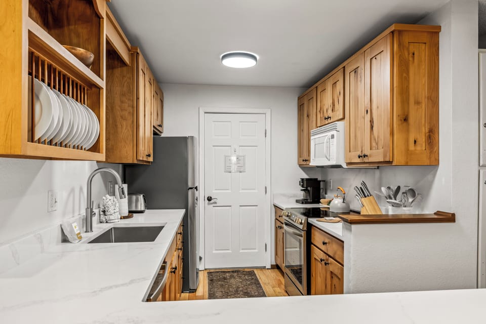 Your fully equipped kitchen features warm wood cabinetry, gleaming countertops, and everything you need to prepare your favorite meals—from morning coffee to a homemade feast.