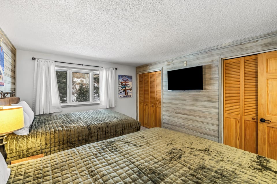 Relax in your cozy bedroom with twin beds, rustic wood accent wall, and mountain views from your window.
