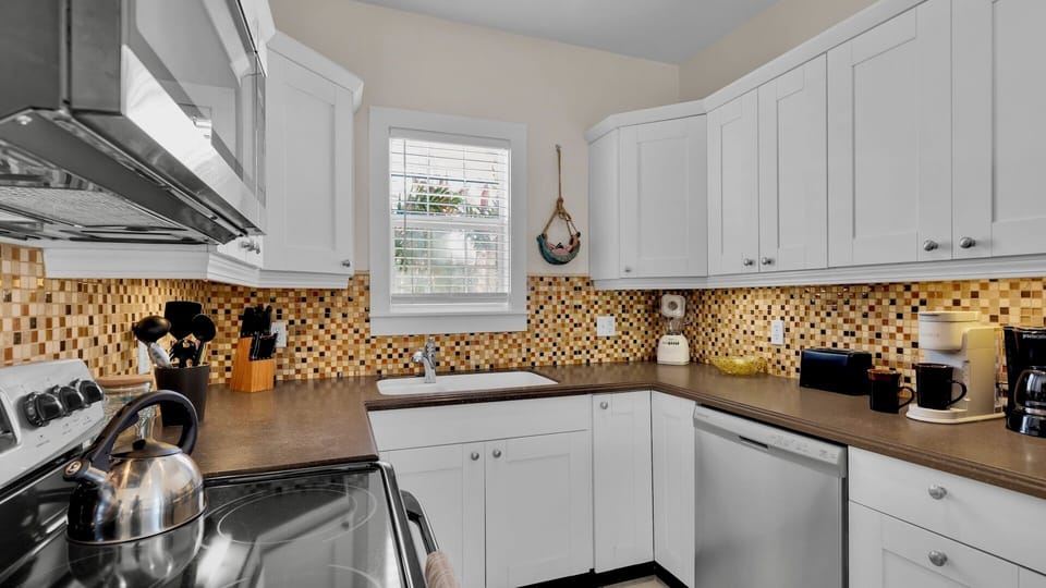 Step into your fully equipped kitchen with warm mosaic backsplash, granite counters, and everything you need for home-cooked meals.