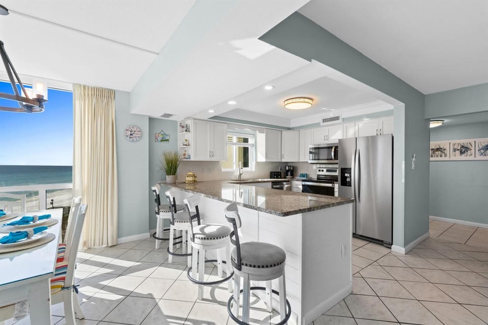 Whip up morning coffee at your oceanfront kitchen island while watching waves through floor-to-ceiling windows—your perfect beach getaway awaits.
