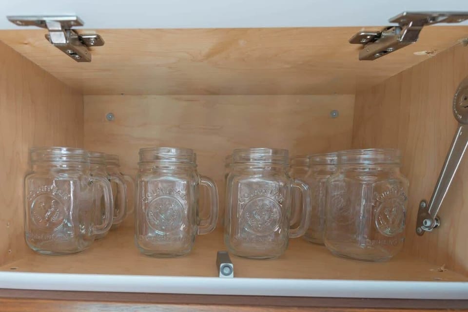 Drawers and cupboards are neatly organized and supplied with essential cookware, dishware, and dining items.
