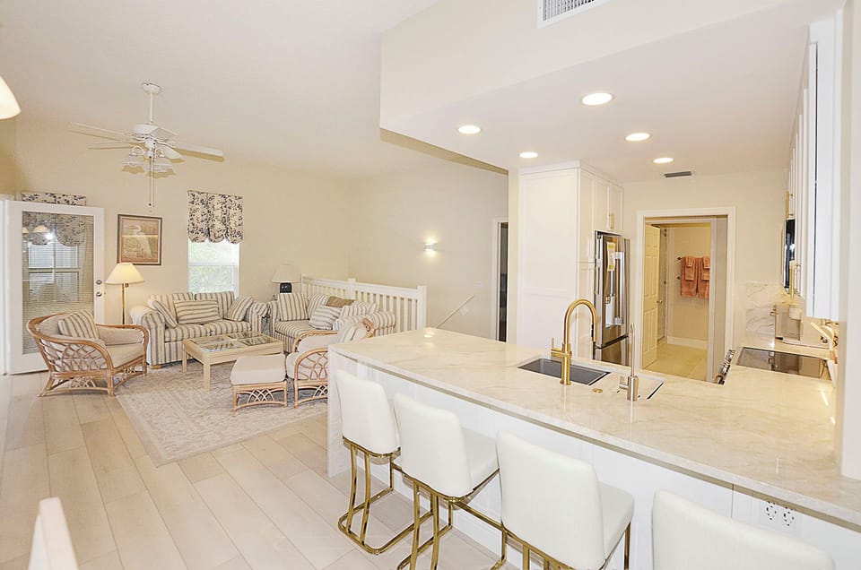 Kitchen / Living. You'll love this bright, open-concept space where elegant white kitchen flows into cozy living area with striped seating perfect for relaxing.