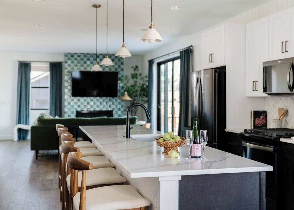 A bright, open kitchen designed for gathering. The oversized island seats the whole crew, with premium appliances, generous prep space, and a seamless flow into the living room—perfect for family meals, group dinners, and entertaining.