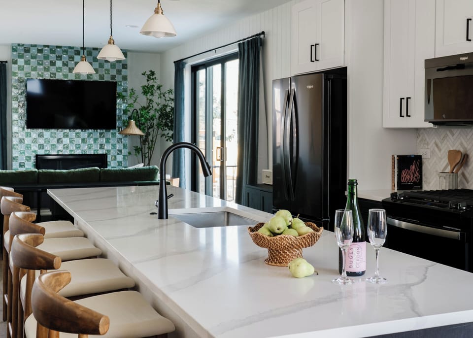 A spacious, open kitchen with a large island and bar seating connects seamlessly to the living area, making it easy to cook, gather, and host together in this Denver vacation rental.