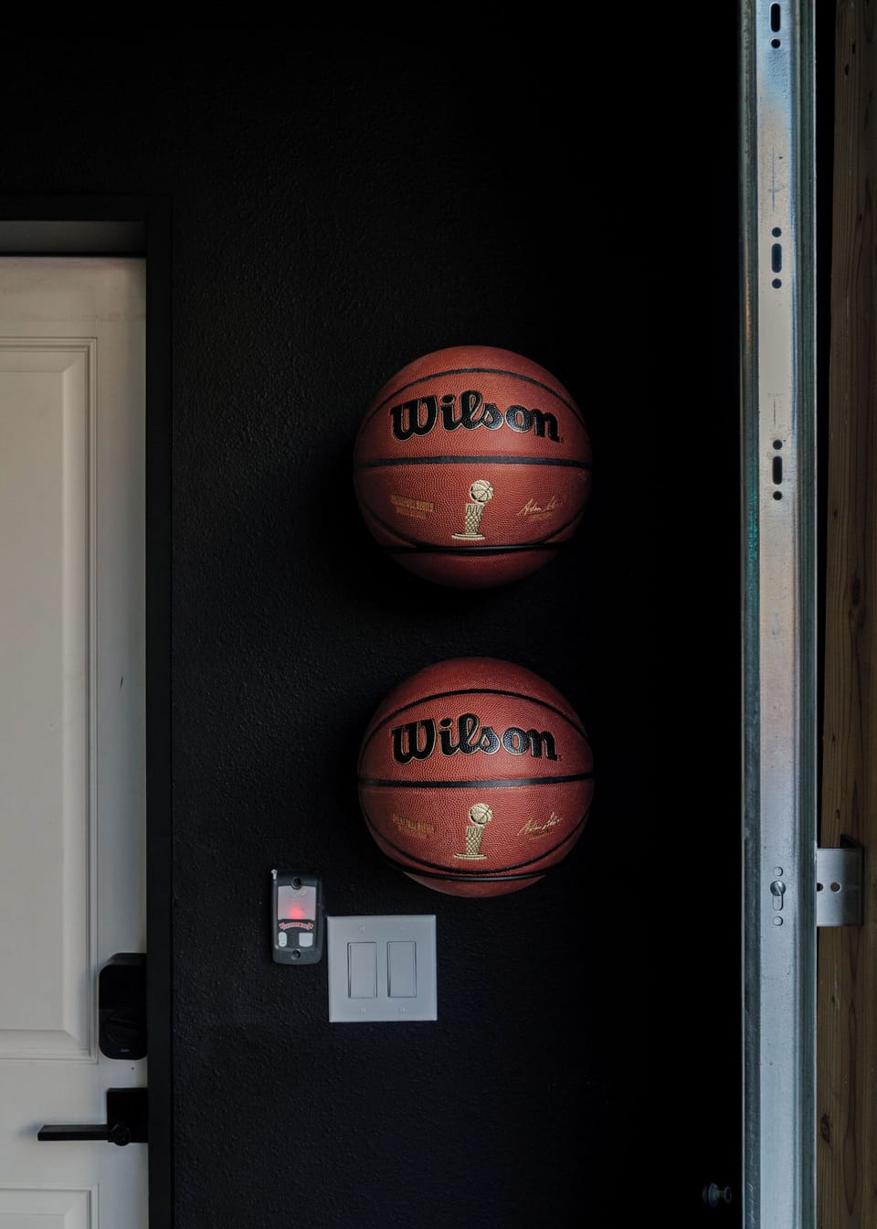 Wall-mounted basketballs ready for pickup games on the private half-court—just one of many thoughtful touches in the heated game room.