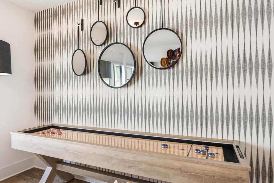 Decorative mirrors frame the shuffleboard table against Nashville-inspired wallpaper. Every angle of this house invites you to play, eat, or just hang with your crew