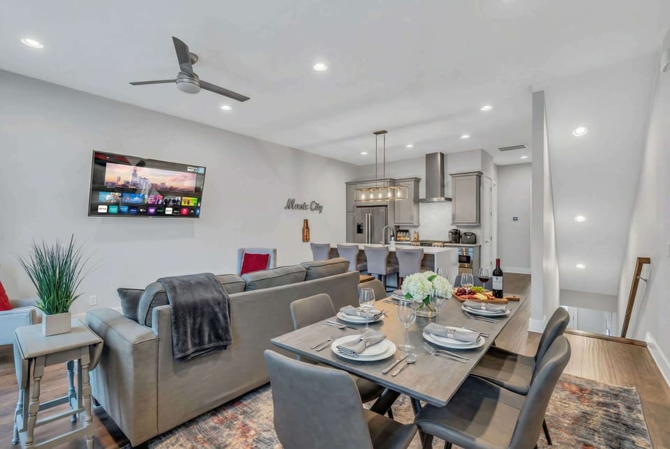 Open concept living and dining with the kitchen and island visible in back. Stairs ascend to the bedrooms above, stairs to the balcony, and a layout that keeps 12 people together without feeling cramped