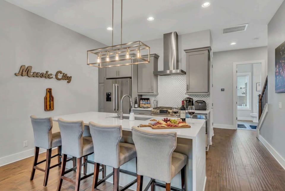 The Music City sign hangs above the kitchen island, a subtle nod to Nashville without trying too hard. Four bar stools and modern lighting set the tone for group meals and drinks