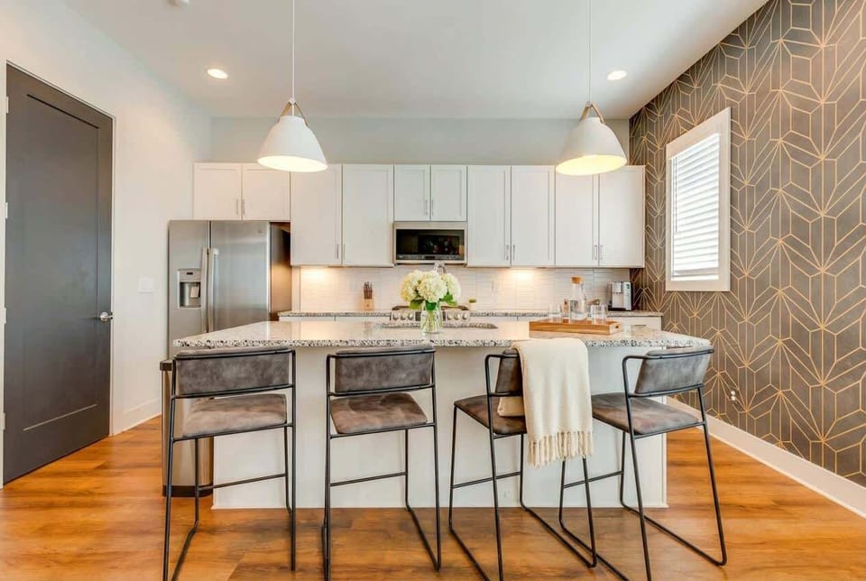 Kitchen built for group cooking, white cabinetry, wood floors, and a big island with bar seating so the cook doesn't miss the action