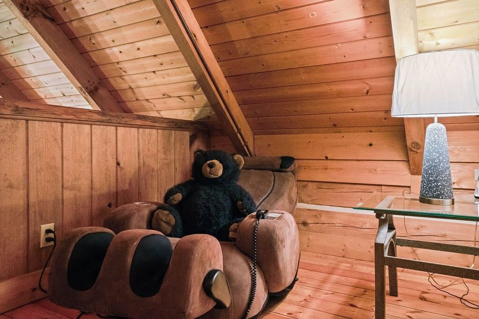 Cozy wood-lined loft nook with playful bear-paw chair and rustic charm