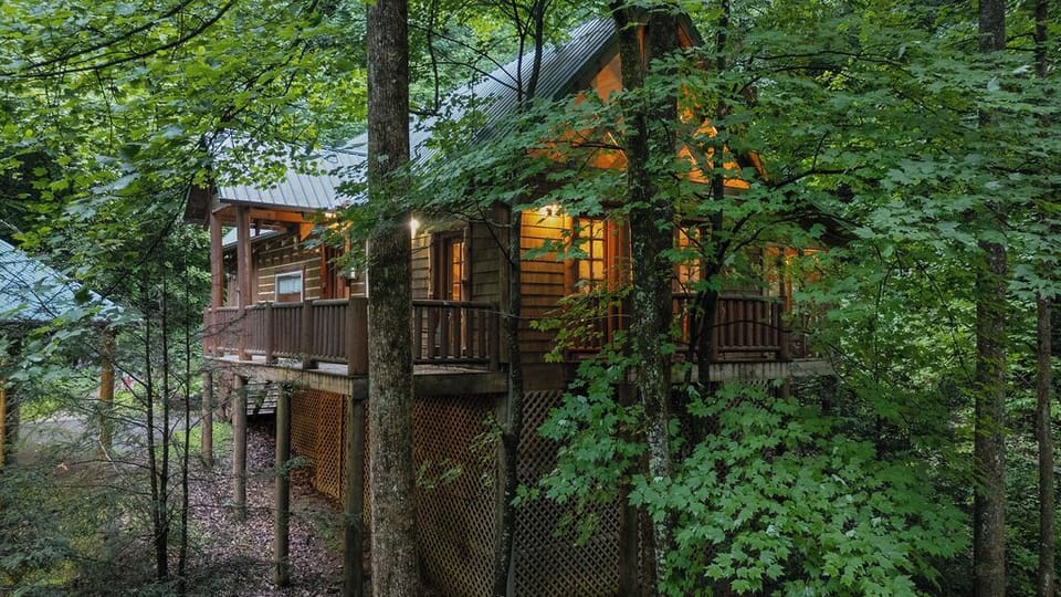 Cozy woodland cabin with glowing lights and a peaceful wraparound deck