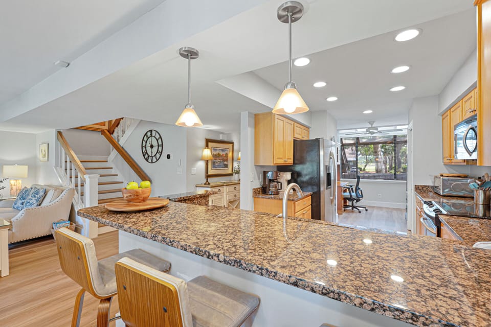 The granite breakfast bar offers seating for casual meals, while the adjacent dining table provides space for group dinners.