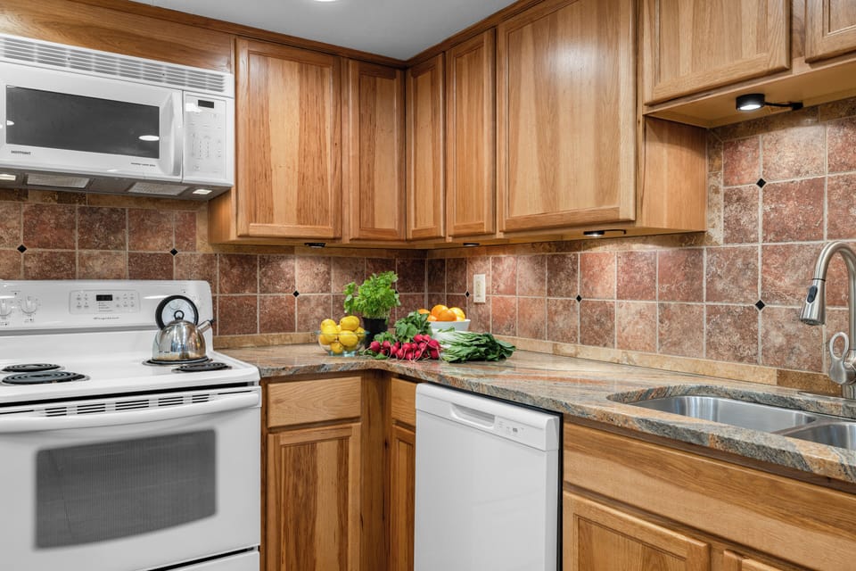 Close-up of the kitchen workspace featuring a clean white stove and dishwasher.