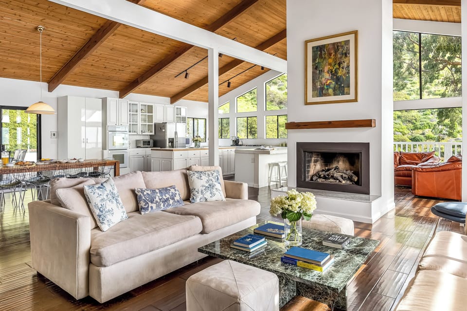 Spacious open-concept living space with a fireplace and vaulted wood ceilings.