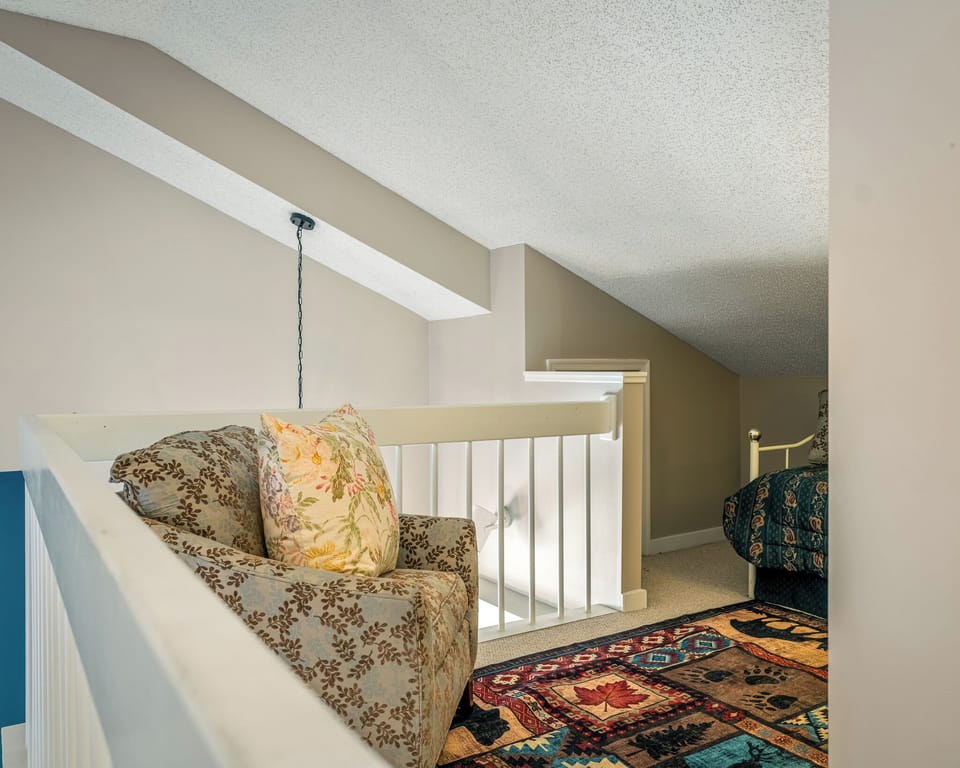 Cozy loft area with a small chair and a twin bed.