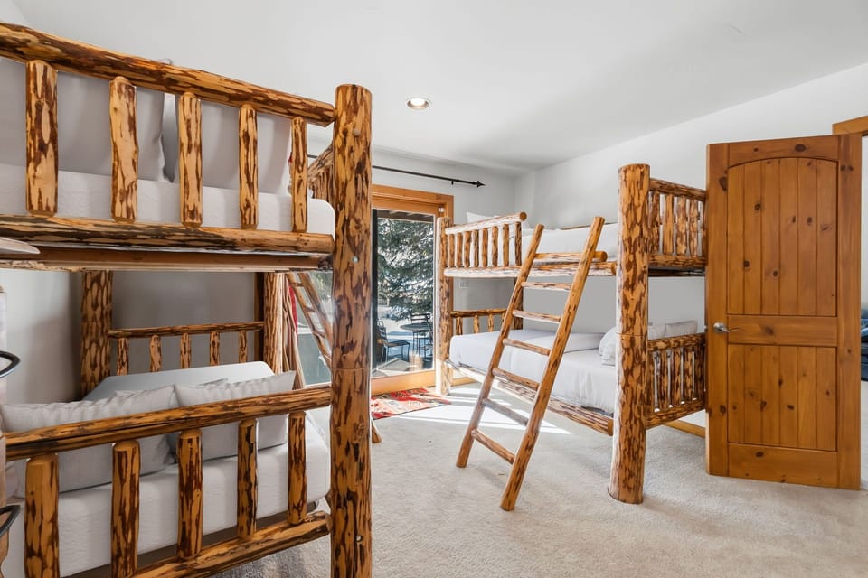 Your rustic bunk room features handcrafted log beds with cozy white linens, perfect for families or groups seeking mountain charm.