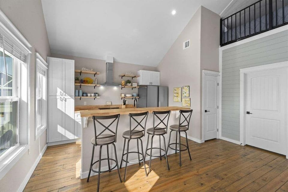 Spacious kitchen with breakfast bar seating, modern finishes, open shelving, and bright coastal-inspired interior.