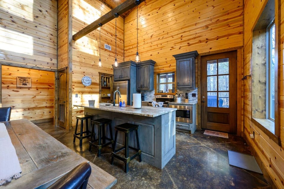 This stunning log cabin kitchen features soaring wood ceilings, custom cabinetry, and gorgeous views of the surrounding landscape.