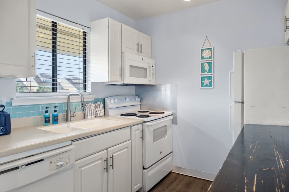 Your bright galley kitchen features white cabinets, modern appliances, and charming coastal touches that make meal prep feel like a breeze.