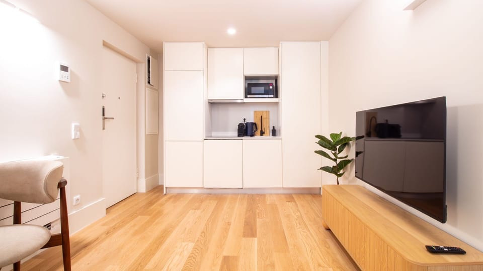 Open-plan living area with minimalist kitchenette, flat-screen TV, and thoughtful layout for a relaxing city break. #OpenPlanLiving #PortoDuplex #HolidayHome #StayWithLovelyStay