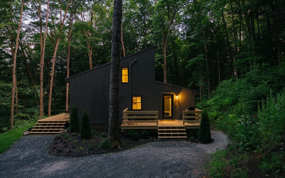 Secluded modern cabin with forest views, warm lights, and private decks
