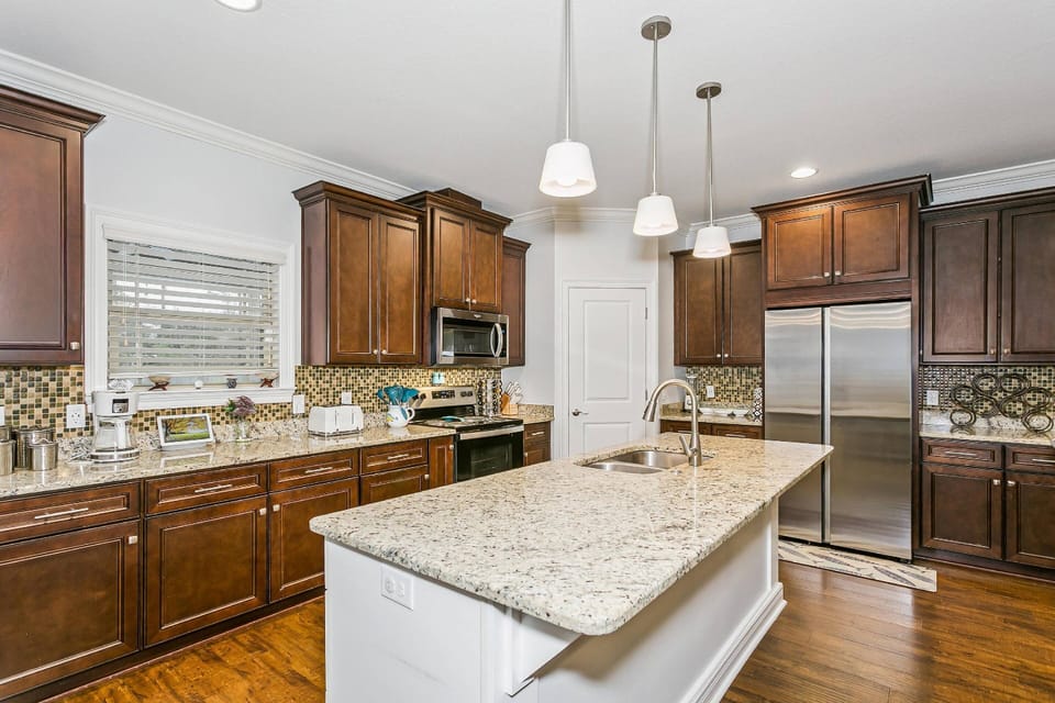 The modern kitchen boasts granite countertops, tile backsplash, and stainless steel appliances