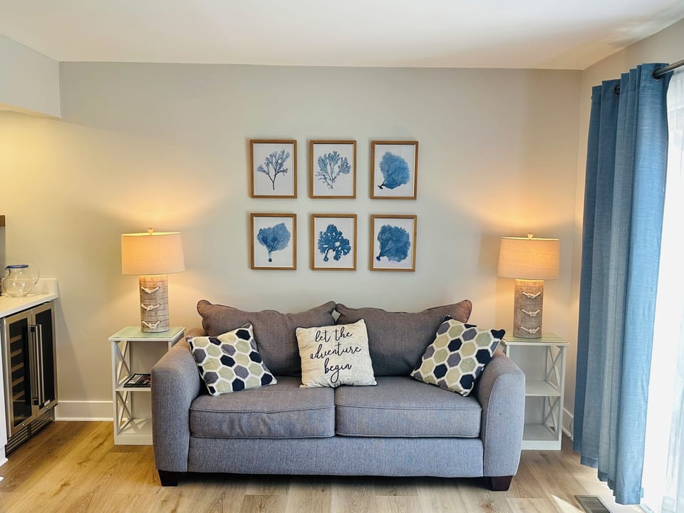 Sunny living room in open-concept first floor has a sofa and loveseat.