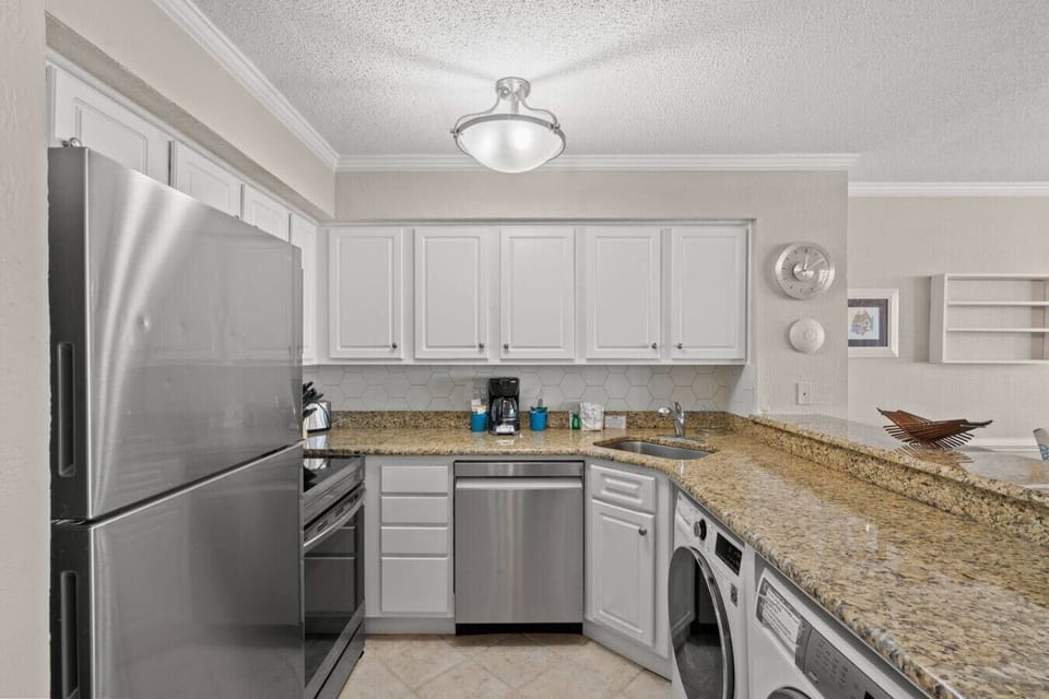 Fully stocked oceanfront kitchen with open bar, featuring washer and dryer, dishwasher, refrigerator, coffee maker, microwave, stove, and complete dishware, cookware, and silverware.