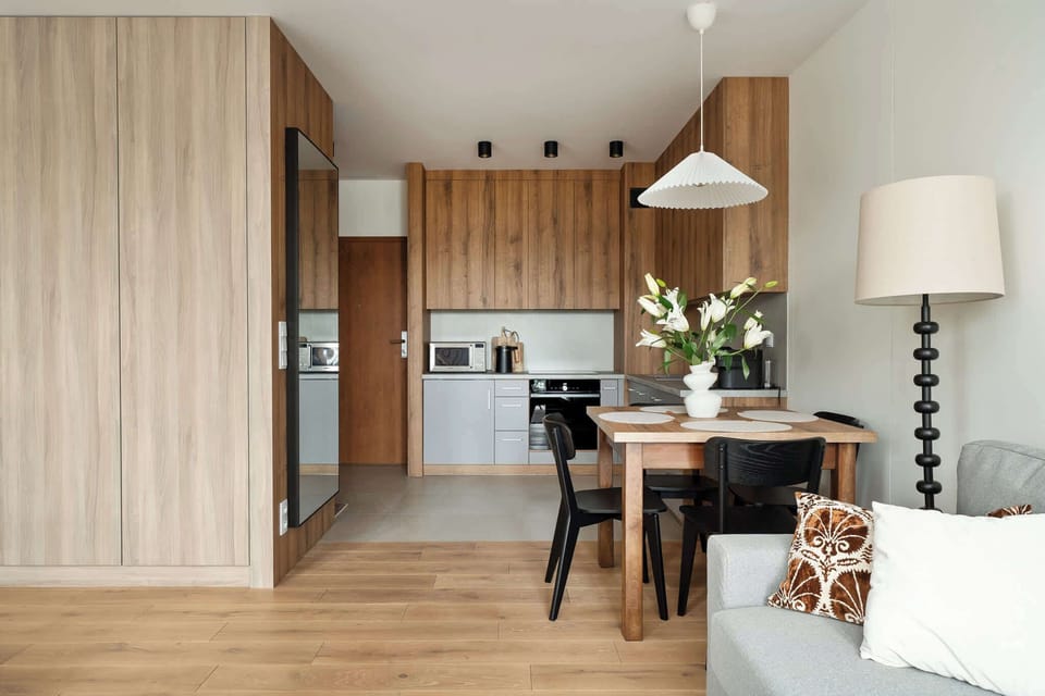 Modern kitchenette with wooden cabinets, built-in appliances, and a dining table for four, creating a cozy and functional cooking space.