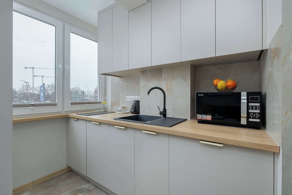 A bright kitchen corner with white cabinetry and a window above the counter. Natural light highlights the clean and functional workspace.