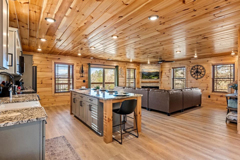 The kitchen flows seamlessly into the living area, blending mountain charm with modern convenience. Prep at the island while still enjoying the fireplace and scenic views beyond.