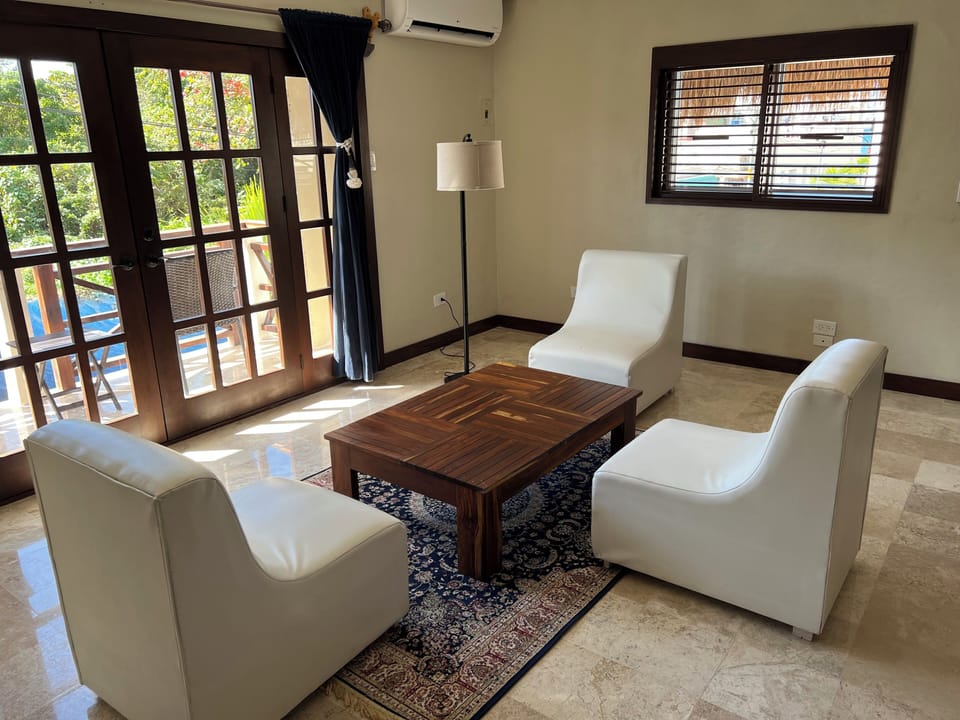 Bright living area with plush white seating, rich wood table, and balcony access