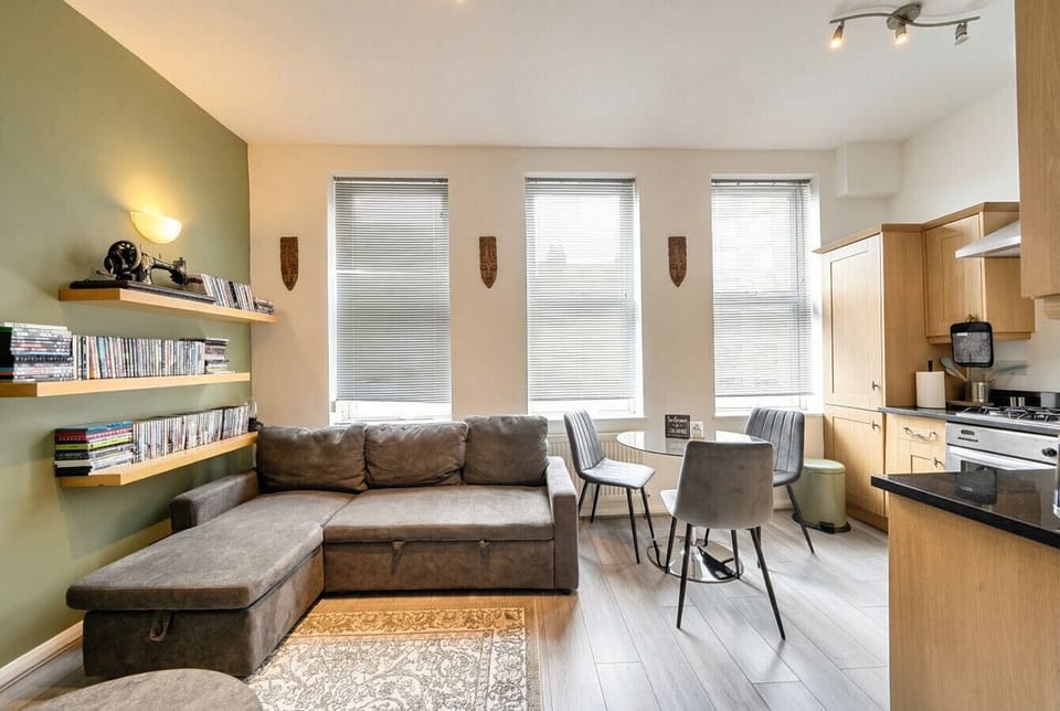 Comfortable sectional sofa and dining area bathed in natural light from three tall windows.