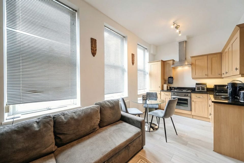 Bright kitchen-diner with warm under-cabinet lighting and seating for two beside the window.
