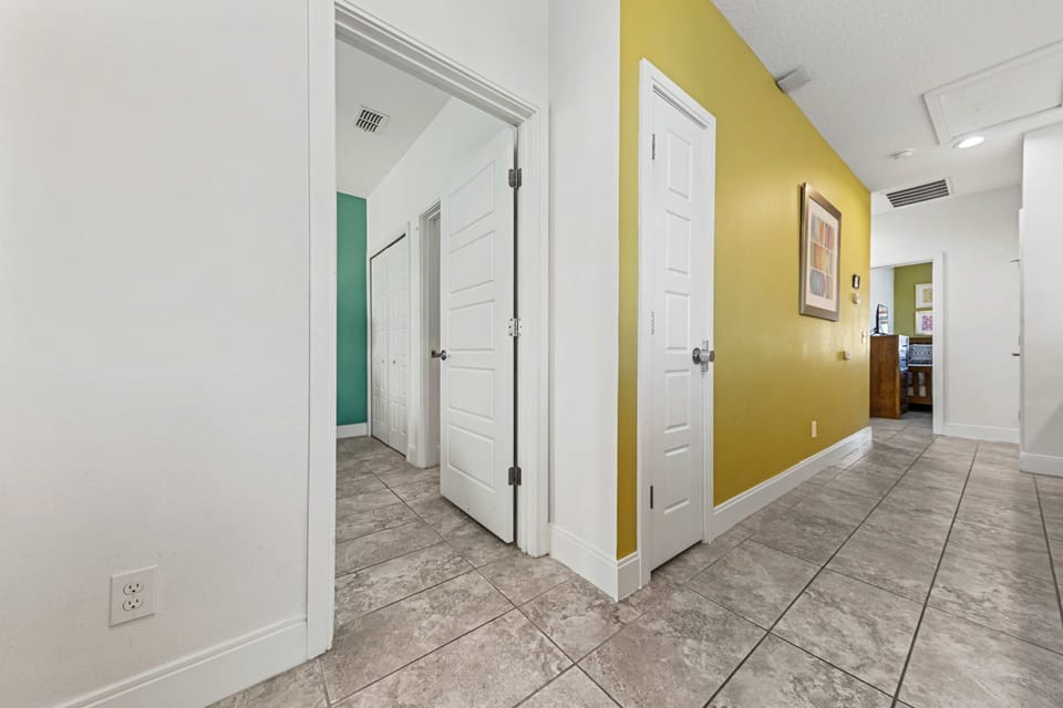 Hallway with tiled floors and colorful accent walls leading to multiple rooms.