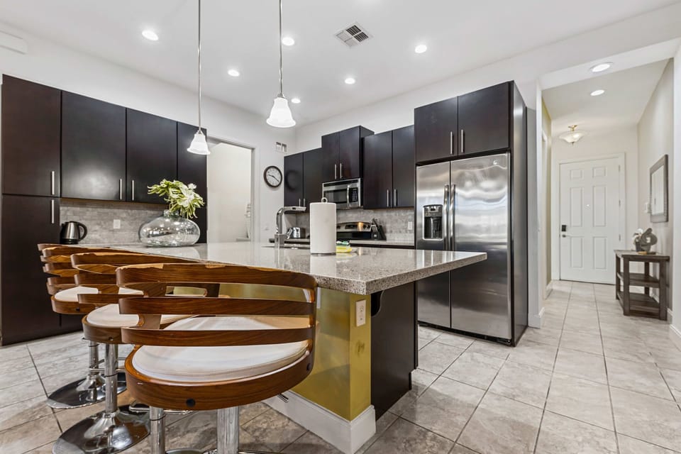 Modern kitchen with dark cabinetry and a large island with wooden bar stools