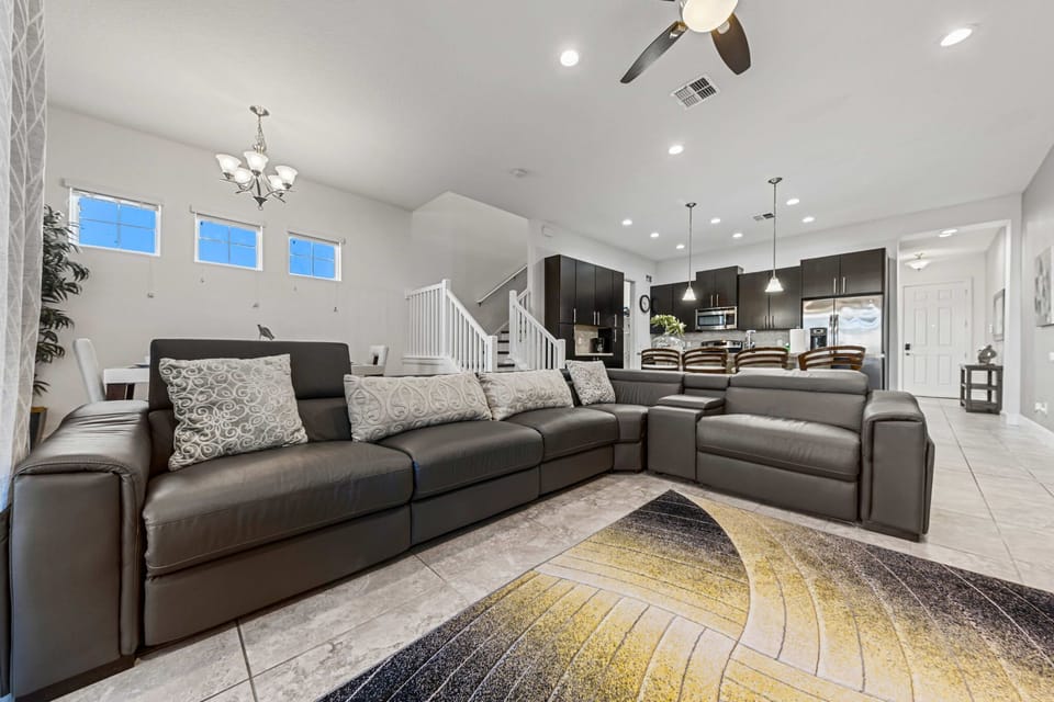 Modern open-concept living area with leather sectional and kitchen bar seating