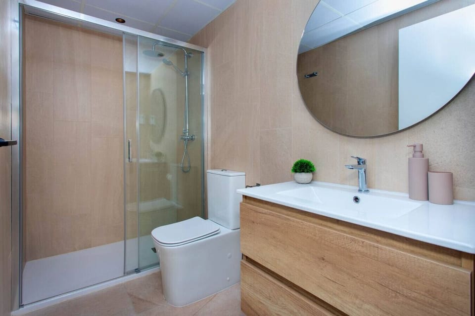 A minimalist rainfall sanctuary designed for ultimate rejuvenation. This glass-enclosed shower features sleek chrome fixtures and warm stone textures, providing a serene, spa-like experience within your private suite. Purity in every detail.