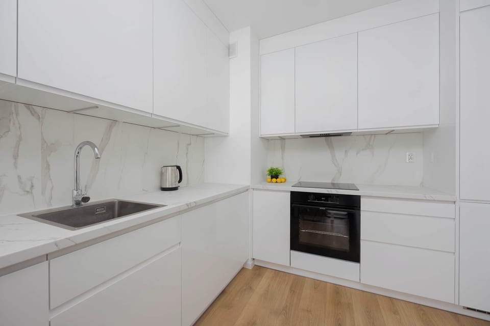 Minimalist white kitchenette with built-in oven and clean design.