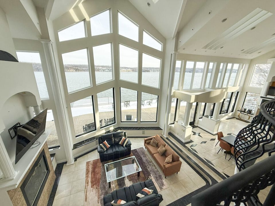 Luxury lakefront retreat with soaring floor-to-ceiling windows, breathtaking panoramic water views, elegant open-concept living, and upscale amenities