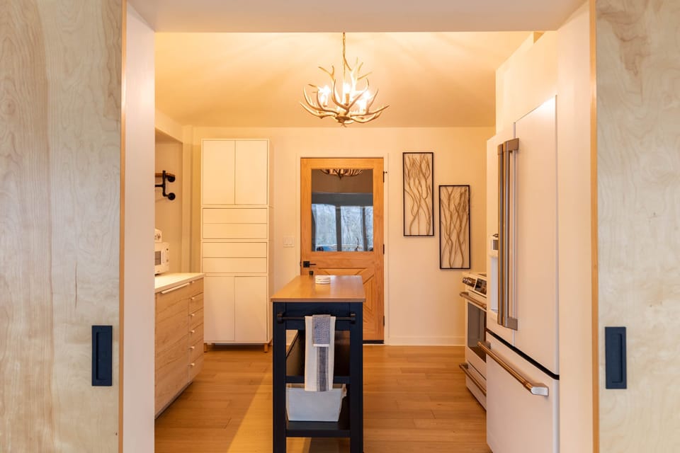 Warm and stylish, the kitchen at Moondrift Retreat draws you in with a rustic antler chandelier and a butcher-block island ready for mountain meals.