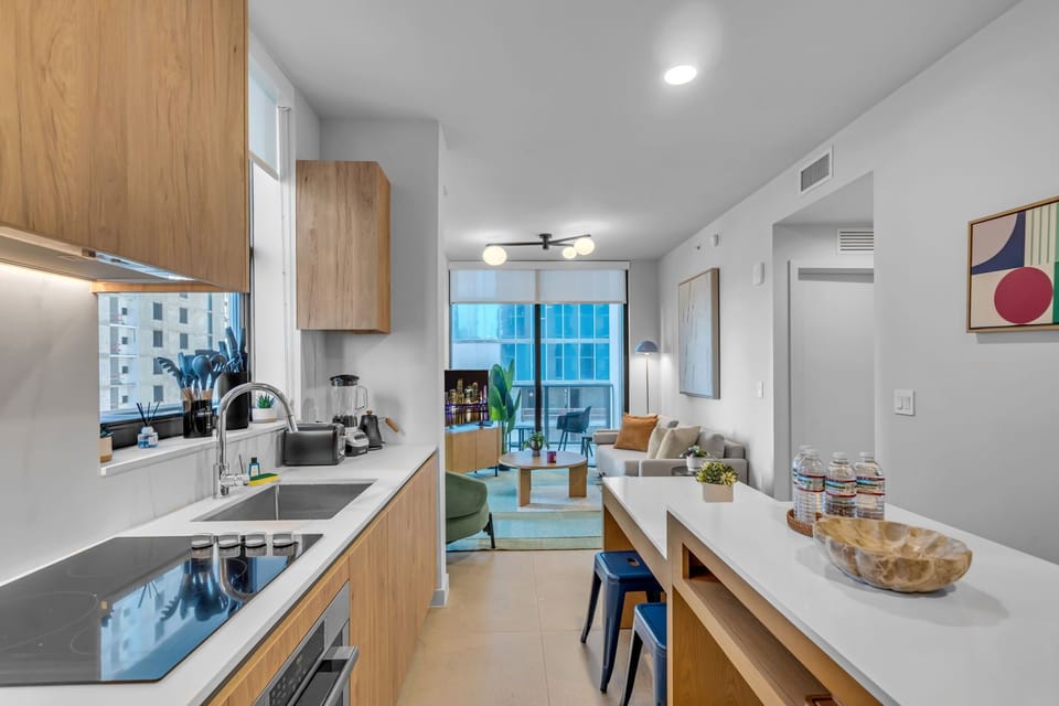 Cook with ease in this sleek, fully-equipped modern kitchen. Boasting beautiful wood cabinetry, pristine countertops, high-end appliances, and an island breakfast bar perfect for your morning coffee