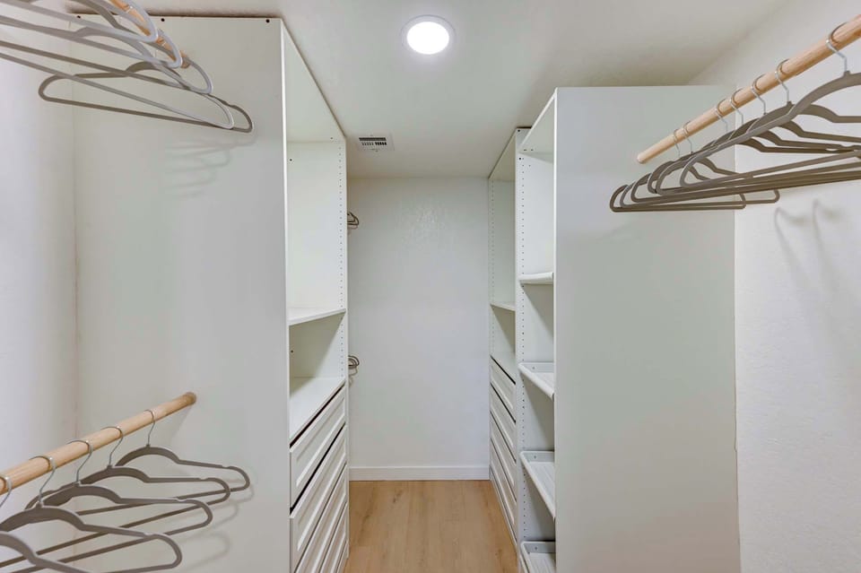 Spacious walk-in closet with built-in shelving and hanging space.