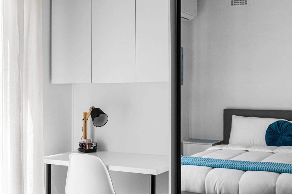 A cosy bedroom with a queen-sized bed and a small table suitable for light work or personal use, offering a quiet and comfortable space to unwind.