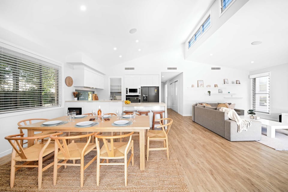The dining area features a large wooden table set for eight guests.