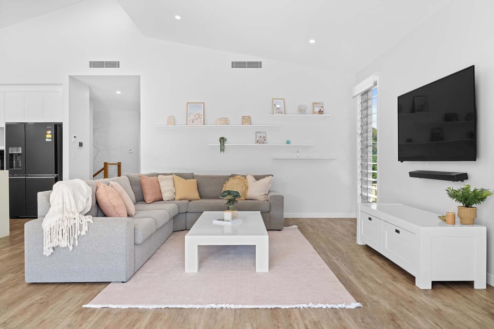 A spacious living area with natural light, soft tones, and a comfortable seating arrangement.