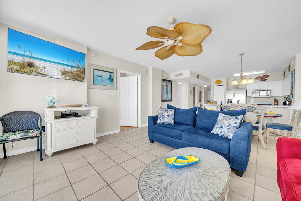 Relax in your bright, coastal-themed living space with comfortable seating and tropical ceiling fan keeping you cool after beach adventures.