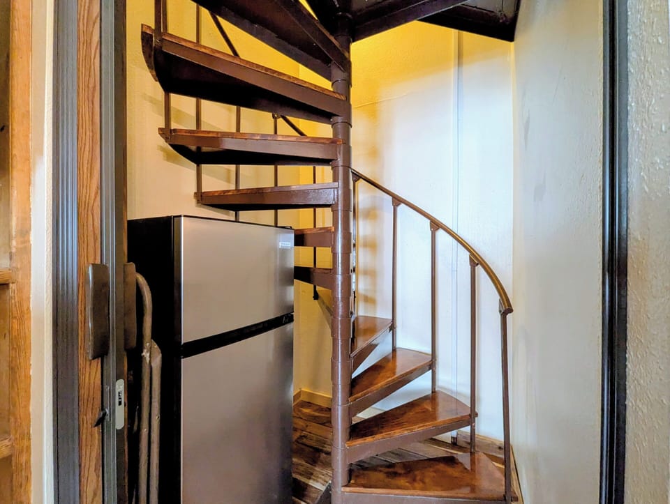 Elegant spiral staircase invites you to explore the upper level of your charming retreat, perfectly curved with warm wood tones.